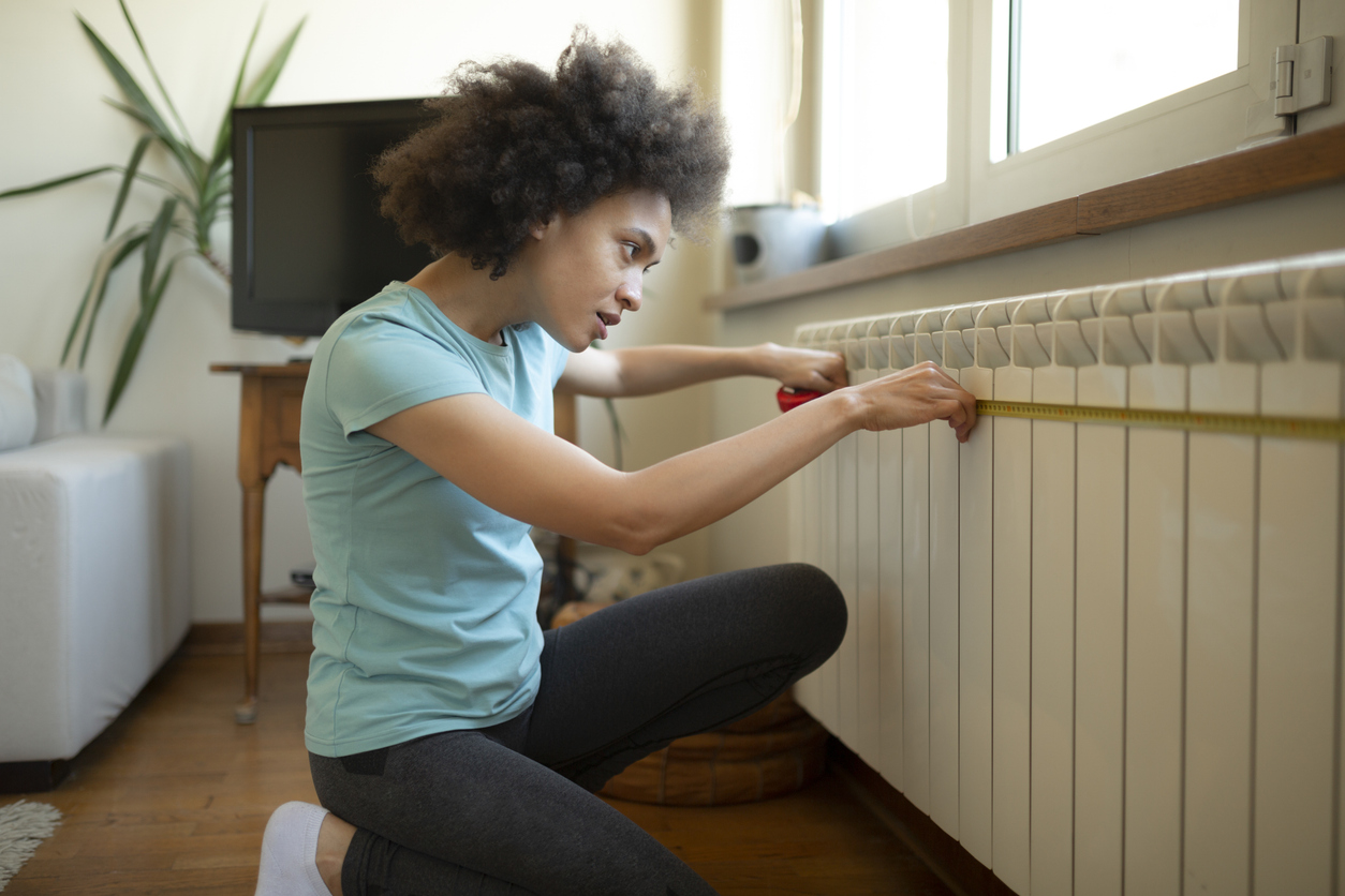 Side view of a female interior designer taking measurements at home Regular Upkeep for Radiator Heating Systems